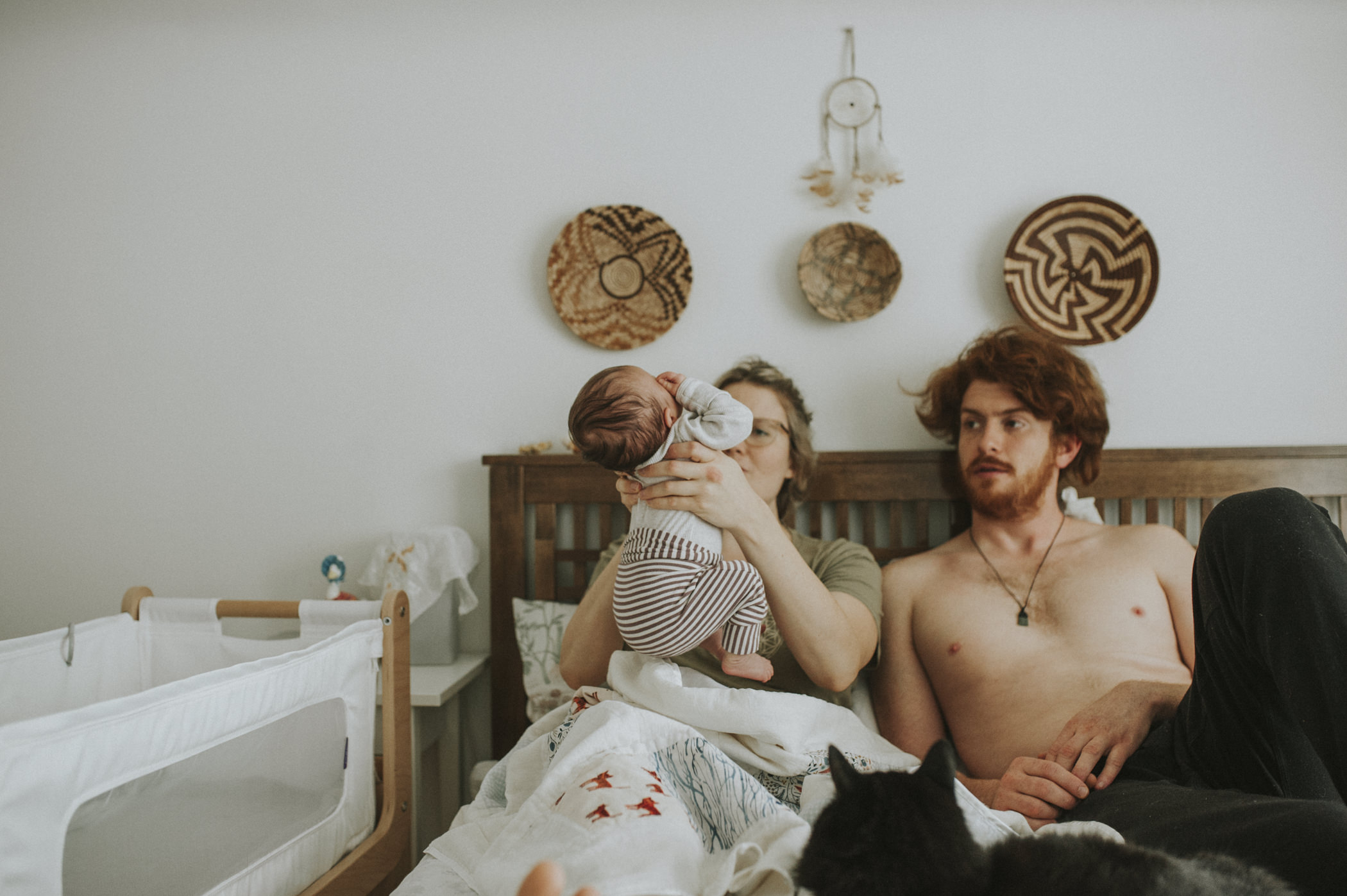 couple with newborn baby, in bed. Baby arching back. 
